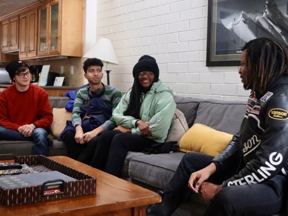 four people sitting on a couch having a conversation